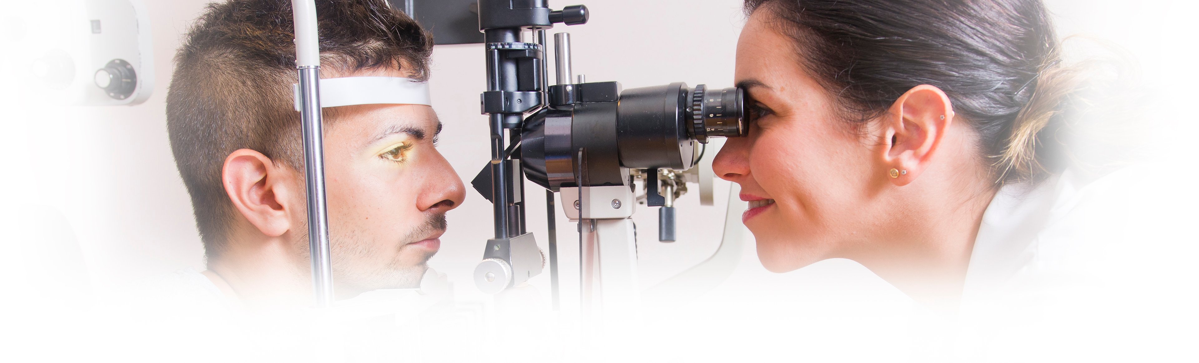 A young woman places a contact lens into her left eye.