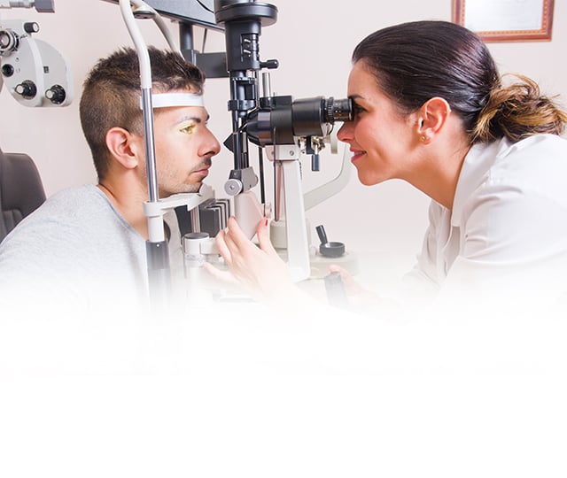 A young woman places a contact lens into her left eye.